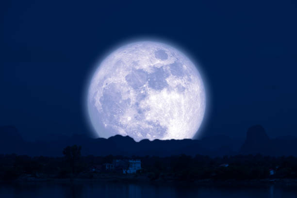 istock Full Snow Moon on night sky back silhouette mountain hill over lake 1255013255