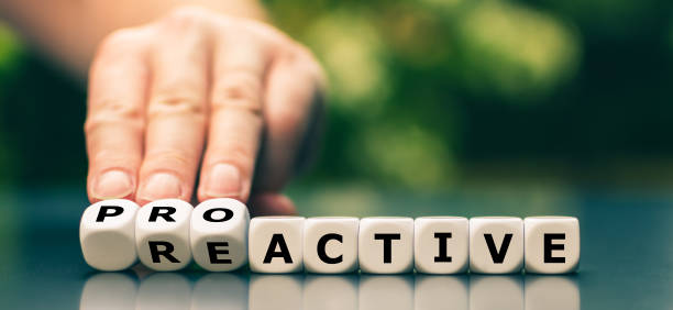 Hand turns dice and changes the word reactive to proactive. stock photo