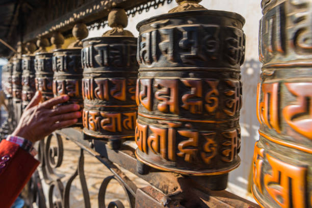 Kathmandu Buddhist prayer wheels spinning at Swayambhunath monkey temple Nepal Pilgrim’s hand spinning polished prayer wheels at Swayambhunath temple in the heart of Kathmandu, Nepal’s vibrant capital city. thamel stock pictures, royalty-free photos & images
