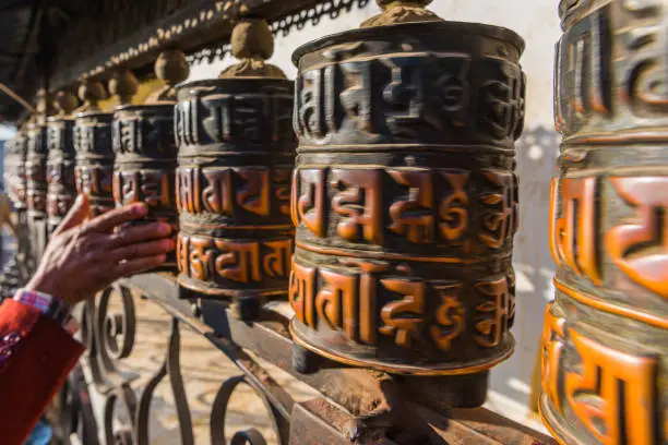 Pilgrim’s hand spinning polished prayer wheels at Swayambhunath temple in the heart of Kathmandu, Nepal’s vibrant capital city.