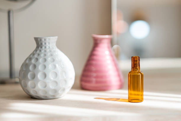 Dressing table with circle mirror, small flower vase in glossy ceramic white and pink vase and reagent bottle on the wooden counter for everyday skin care and cosmetic.