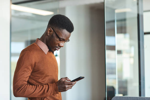 istock Young African-American Man Using Smartphone in office 1255016580