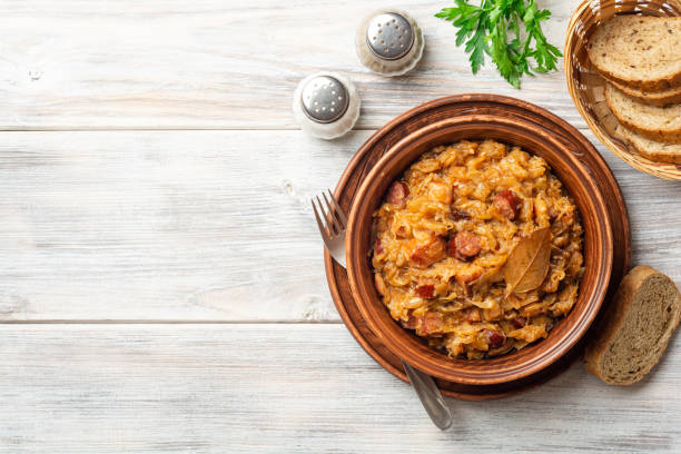 plato tradicional polaco bigos en cuenco de cerámica sobre mesa de madera rústica - bigos fotografías e imágenes de stock