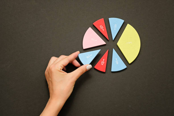 istock Colorful fraction circles arranged into a circle graph and hand, black background. 1255016907