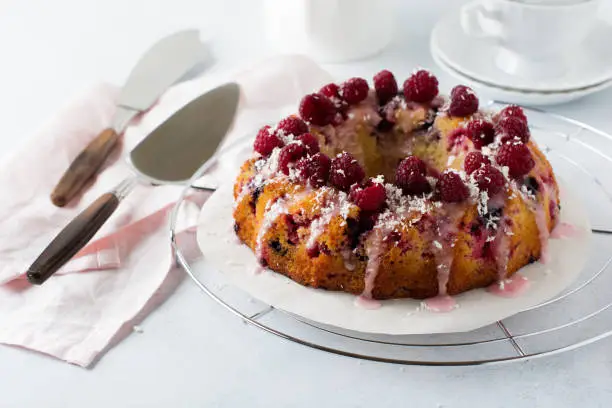 Lemon bundt-cake with raspberries on a light background. Selective focus.