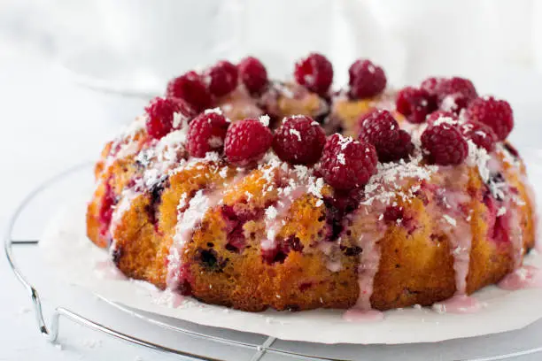 Lemon bundt-cake with raspberries on a light background. Selective focus.
