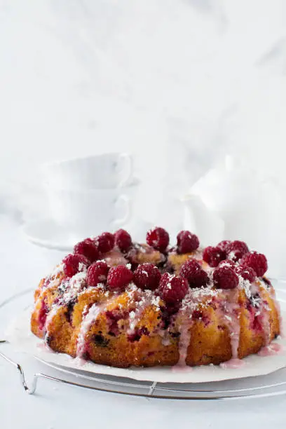 Lemon bundt-cake with raspberries on a light background. Selective focus.