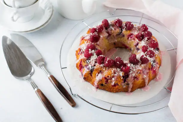 Lemon bundt-cake with raspberries on a light background. Selective focus.