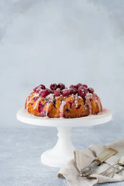 Lemon bundt-cake with raspberries on a light background. Selective focus.