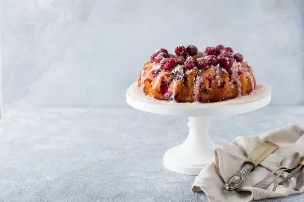 Lemon bundt-cake with raspberries on a light background. Selective focus.