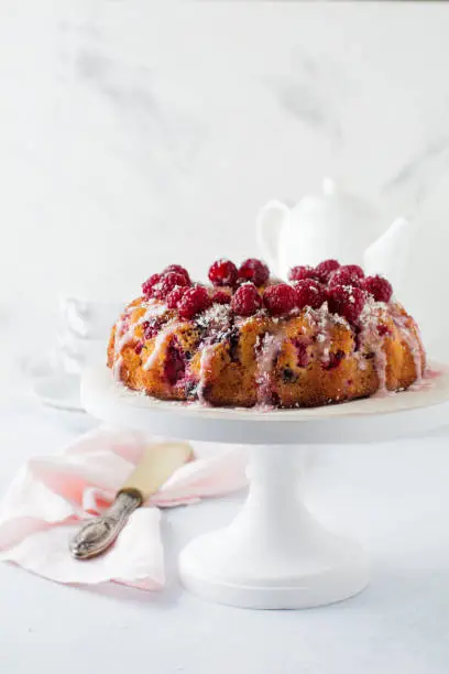 Lemon bundt-cake with raspberries on a light background. Selective focus.