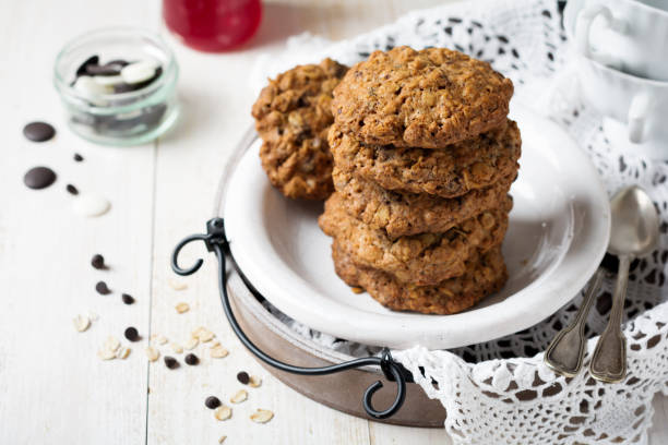 istock Stack of oatmeal cookies with chocolate on a light background with flakes and a bottle of milk. Selective focus. 1255018349