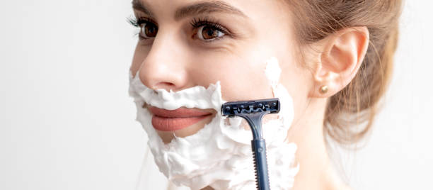 istock Woman shaving her face by razor 1255020424