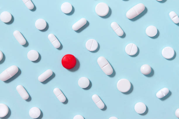 белые таблетки на синем фоне - capsule pill medicine red стоковые фото и изображения
