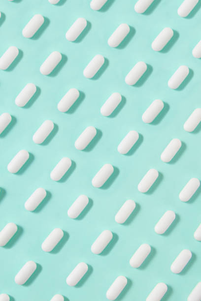 istock White Pills on Mint Green Background 1255023882