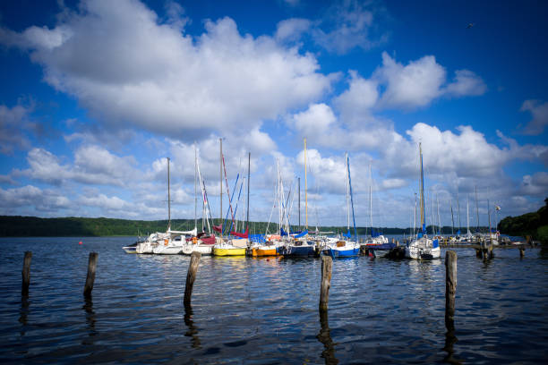 no lago muitos veleiros estão ancorados um ao lado do outro em um estágio de pouso e o céu é azul com nuvens brancas - plank boardwalk pontoon bridge summer - fotografias e filmes do acervo