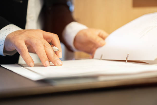 istock Document Report and business busy Concept: Businessman Manager checking and signing documents reports papers with calculator, laptop computer on stacks of paper files in modern office. 1255023998