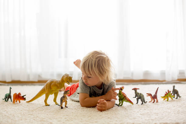 istock Blond toddler child, playing with dinosaurs at home 1255026237