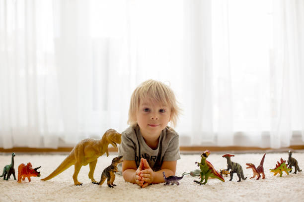 istock Blond toddler child, playing with dinosaurs at home 1255026258