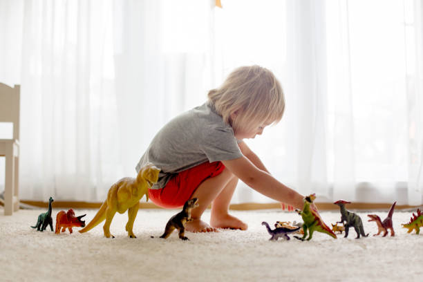 istock Blond toddler child, playing with dinosaurs at home 1255026277
