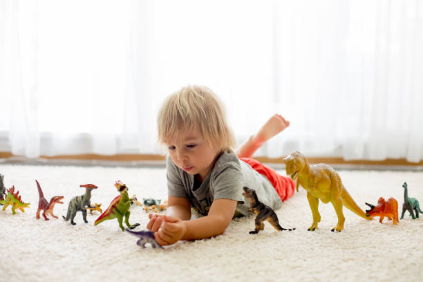 istock Blond toddler child, playing with dinosaurs at home 1255026302