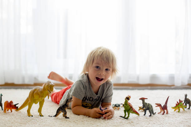 istock Blond toddler child, playing with dinosaurs at home 1255026340