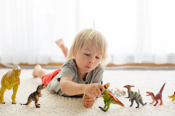 istock Blond toddler child, playing with dinosaurs at home 1255026357