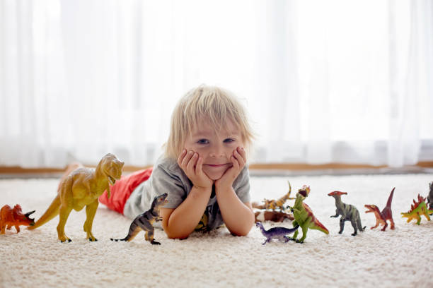 istock Blond toddler child, playing with dinosaurs at home 1255026397
