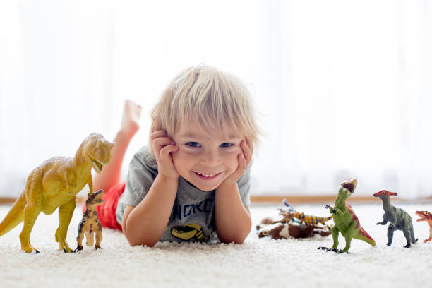 istock Blond toddler child, playing with dinosaurs at home 1255026462