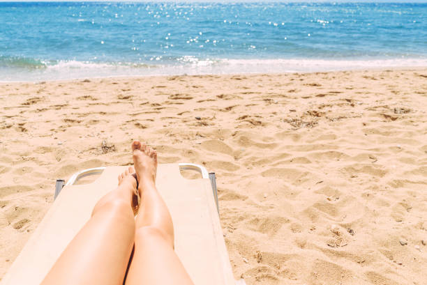 istock Female legs sunbathing on the beach 1255026486