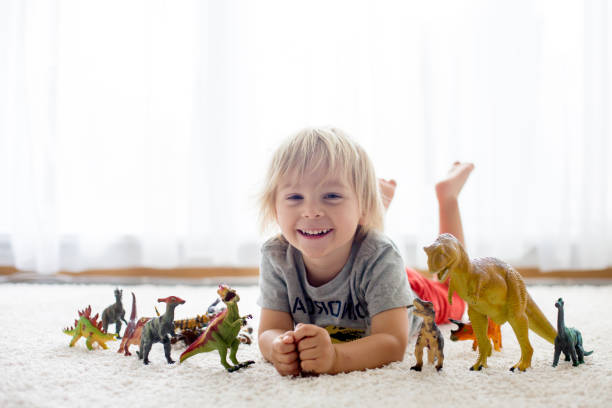 istock Blond toddler child, playing with dinosaurs at home 1255026503