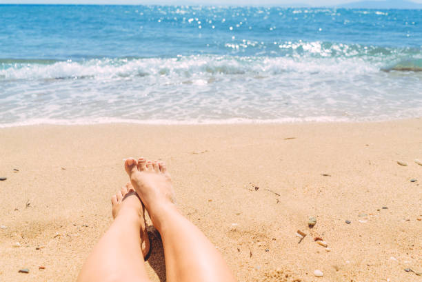 istock Female legs sunbathing on the beach 1255026504