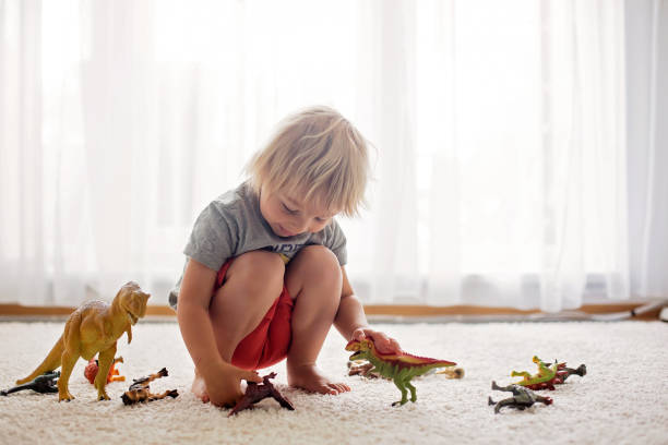 istock Blond toddler child, playing with dinosaurs at home 1255026523