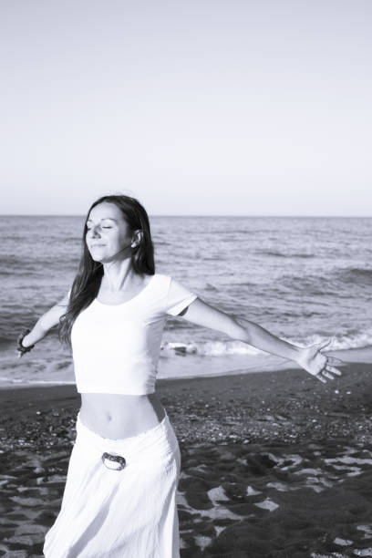 istock Woman dressed in white barefoot on the beach sand. Smiling 1255026619