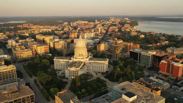 Photo of Aerial view of City of Madison. The capital city of Wisconsin from above. Drone flying over Wisconsin State Capitol in downtown. Sunny morning, sunrise (sunset), sunlight, summertime