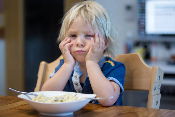 istock Cute blond boy, child eating spaghetti at home 1255027696