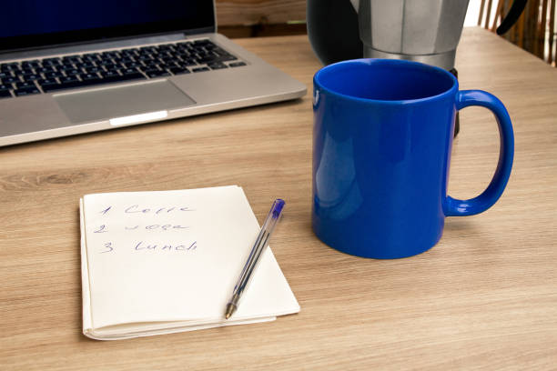 Good morning with coffee. A cup of coffee in blue. Notepad with daily routine. Notebook.\