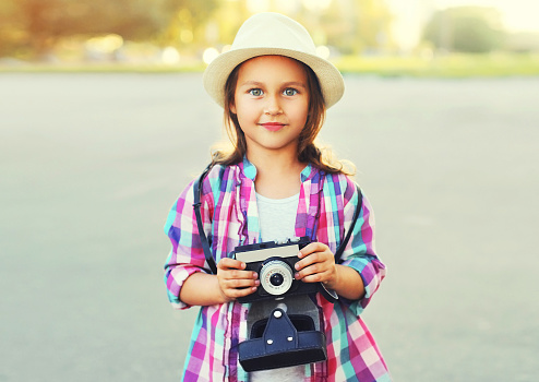 Close up child with retro camera taking picture wearing a summer straw hat outdoors