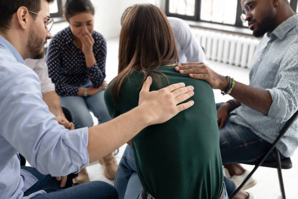 During group therapy session members supporting crying desperate girl Multi ethnic people gathered together sitting on chairs in circle supporting crying desperate girl during group therapy session, medical detox center, psychological help assistance at meeting concept addict stock pictures, royalty-free photos & images