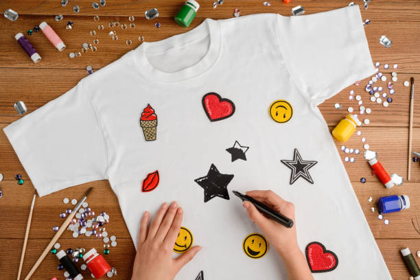 Girl painting stars on a white t-shirt with different embroidered patches Girl painting stars on a white t-shirt with different embroidered patches. Hobby, fashion and custom design DIY project. DIY and Customization clothing stock pictures, royalty-free photos & images