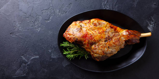 istock Roasted lamb leg on a plate. Black background. Copy space. Top view. 1255035705