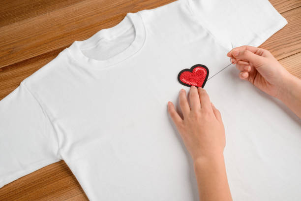istock Girl applying embroidered heart patch to a plain white t-shirt 1255035953