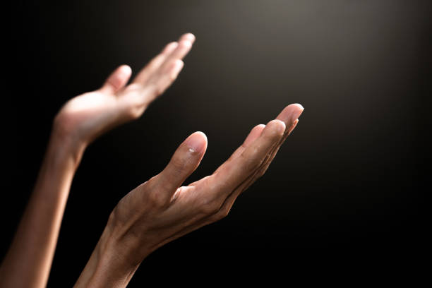 istock woman's hands joined praying with black background 1255037204