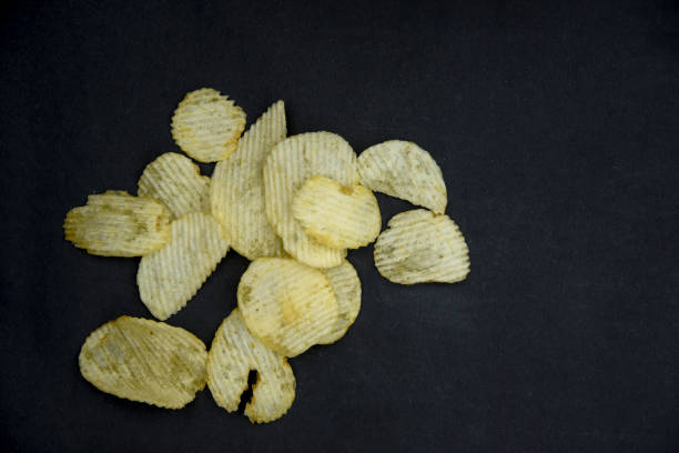 istock Crispy potato chips in bowl on dark table 1255040038