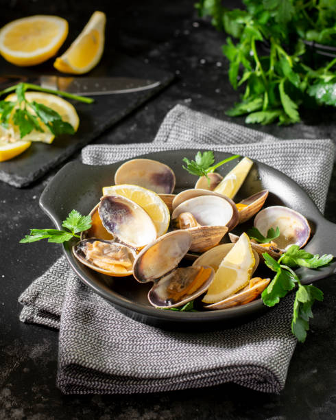istock Cooked clams in a black ceramic plate on the black kitchen table. Seafood dish. The view from the top 1255040886