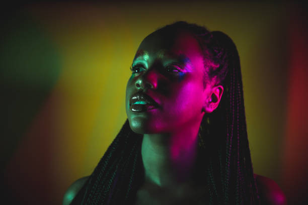 Dark studio shot of a young woman with a multi colored light.