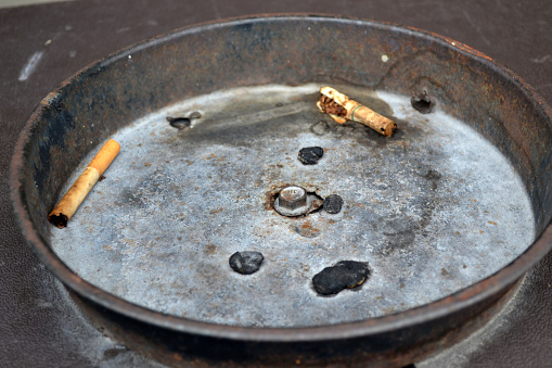 Cigarette in ashtray on diner table.