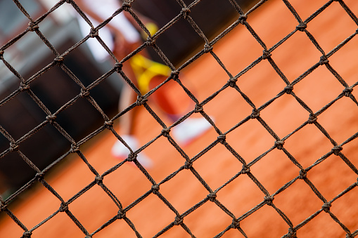 Close up of a tennis net with an unrecognizable player at background - Lifestyles