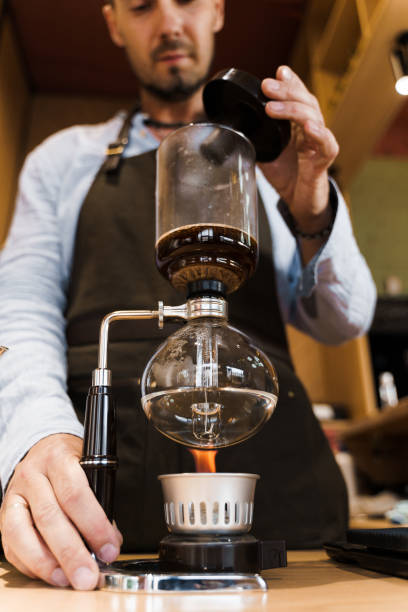 istock Syphon coffee brewing process. Close up syphon is heating by fire. Brewing photo on the fire. Alternative method of coffee making. Vertical photo for advert in social networks 1255051273