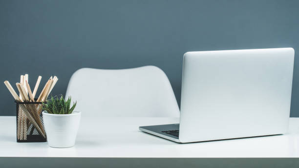 Minimal background image of opened laptop at desk in home office in black and white interior, copy space